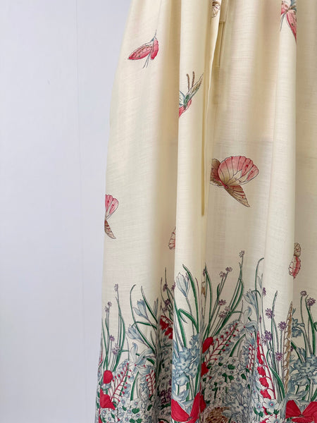 Vintage 1970s maxi dress featuring a floral and butterfly print, short sleeves, and a softly draped, full-length skirt.