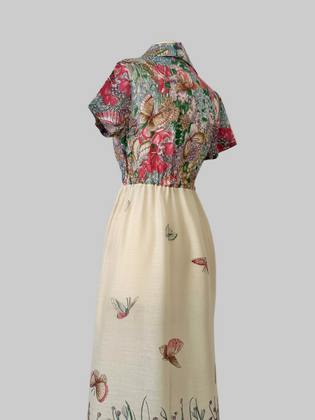 Vintage 1970s maxi dress featuring a floral and butterfly print, short sleeves, and a softly draped, full-length skirt.
