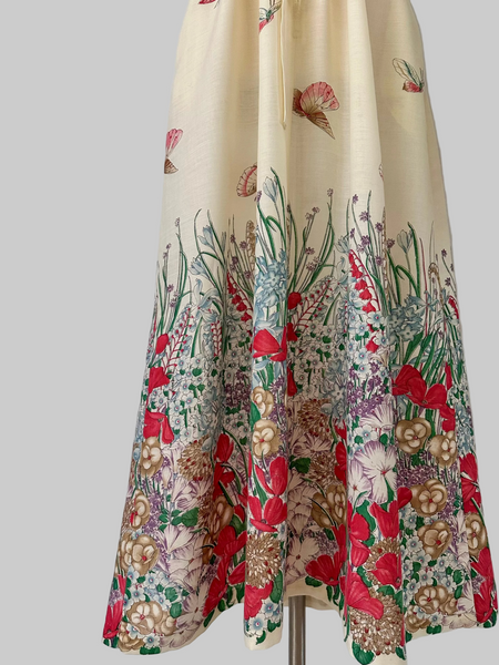 Vintage 1970s maxi dress featuring a floral and butterfly print, short sleeves, and a softly draped, full-length skirt.