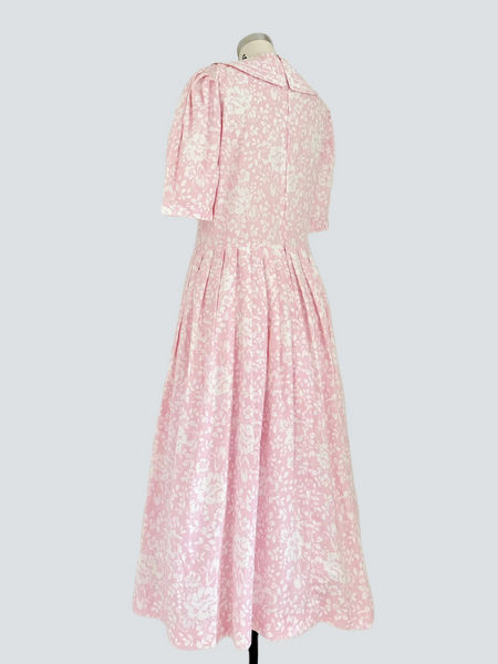 1980s Laura Ashley pink floral cotton dress with sailor collar, white piping, satin ribbon neckline, three-quarter sleeves, and full pleated skirt.