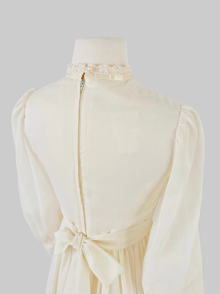 1970s Gunne Sax vintage cream gown with an embroidered yoke, lace-trimmed high neckline with bow tie, faux-pearl buttoned bodice