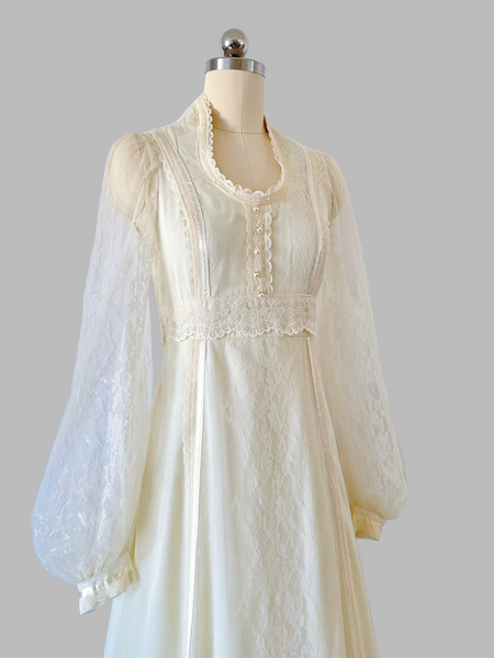 Vintage 1970s Gunne Sax gown in a soft candlelight hue, featuring a lace-adorned bodice with faux-pearl buttons, sheer patterned lace sleeves, and a tiered lace-trimmed skirt.