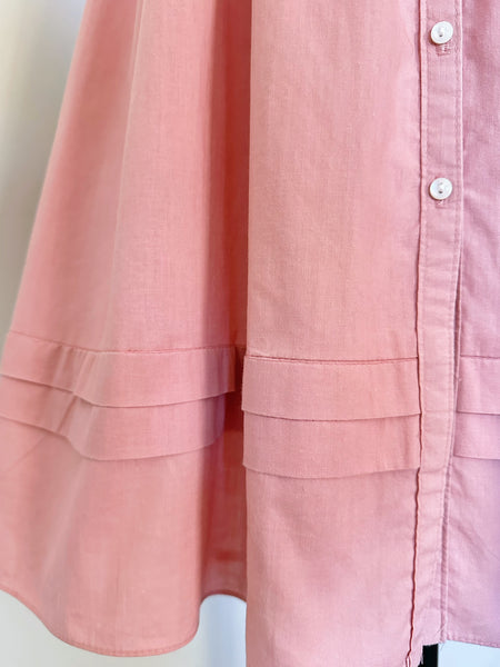 Close-up of a dusty pink button-up 70w Gunne Sax dress with tiered ruffle details on the sleeves and front pleats, featuring white buttons.