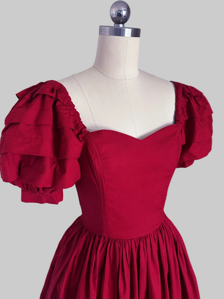 1980s Laura Ashley Red cotton dress with a fitted boned sweetheart bodice, tiered puff sleeves, and full sweeping skirt