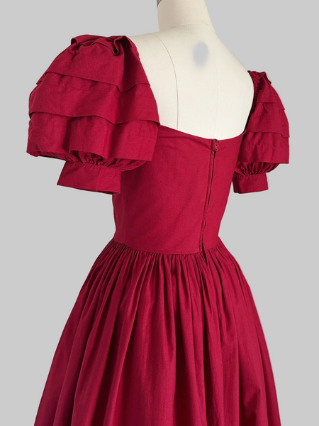 Detail of 1980s Laura Ashley Red cotton dress with a fitted boned sweetheart bodice, tiered puff sleeves, and full sweeping skirt