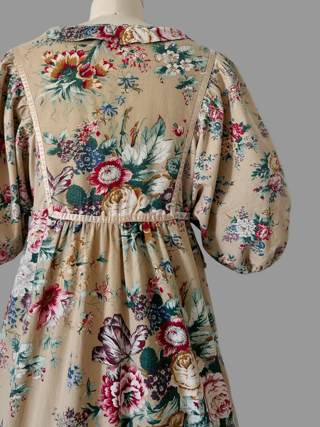 Back view of 1970s honey-beige cotton floral  midi dress by Plain Jane by Danuta featuring ribbon trim, puffed sleeves, empire waist with side ties, and a softly gathered flared skirt.